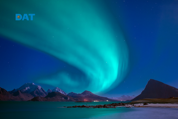 Cực quang dạng màn (Curtains) màu xanh lục xuất hiện trên bầu trời đêm phía trên dãy núi phủ tuyết.